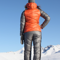 woman on top of a snowy mountain looking out at the view wearing skhoop daria puffy down pants