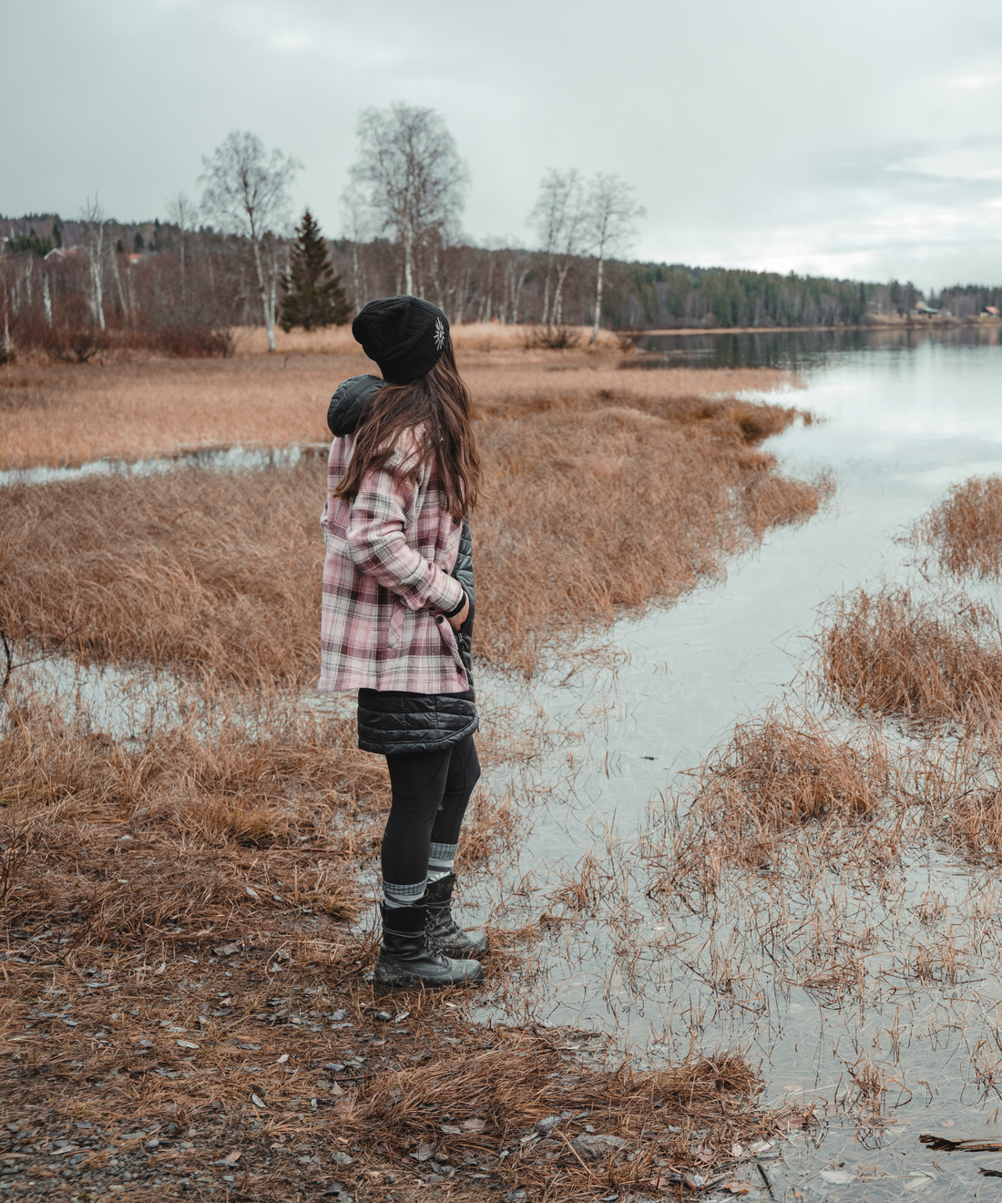 woman standing on the edge of a marsh wearing pink skhoop flannel