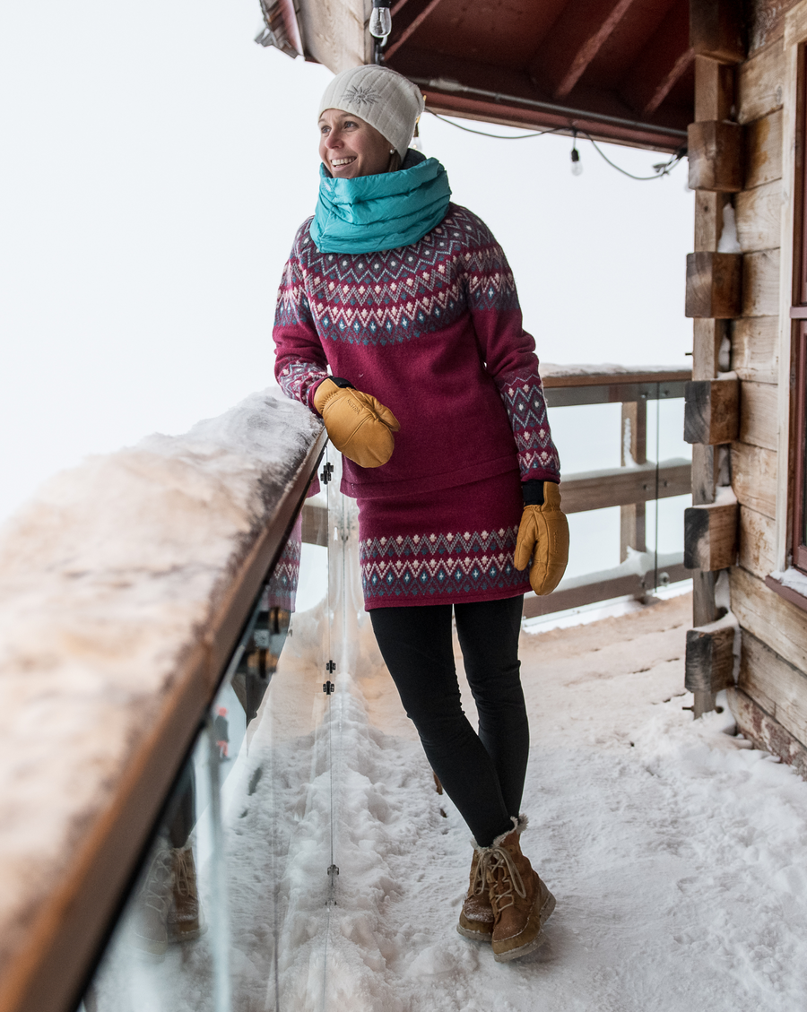 woman standing on snowy deck in skhoop wool sweater and skirt