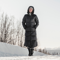 woman walking down a snowy street wearing long down hella coat from skhoop