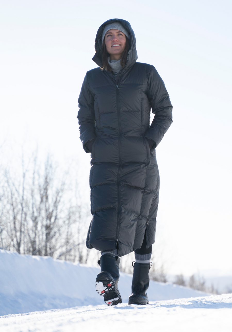 woman walking down a snowy street wearing her long puffy down coat from skhoop