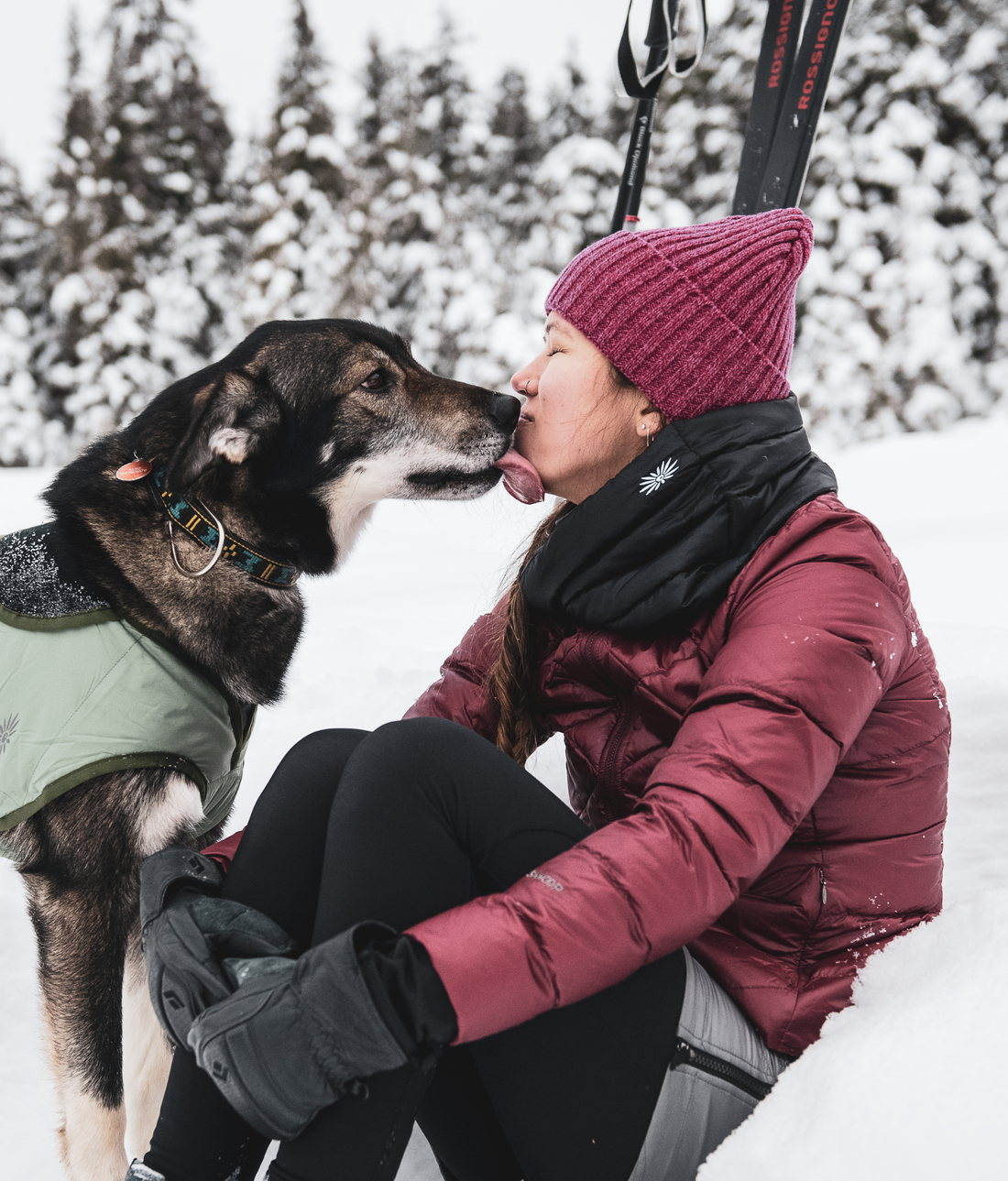 woman getting kissed by her dog outside in the snow while wearing a skhoop outfit