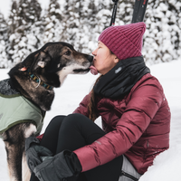 woman getting kissed by her dog outside in the snow while wearing a skhoop outfit