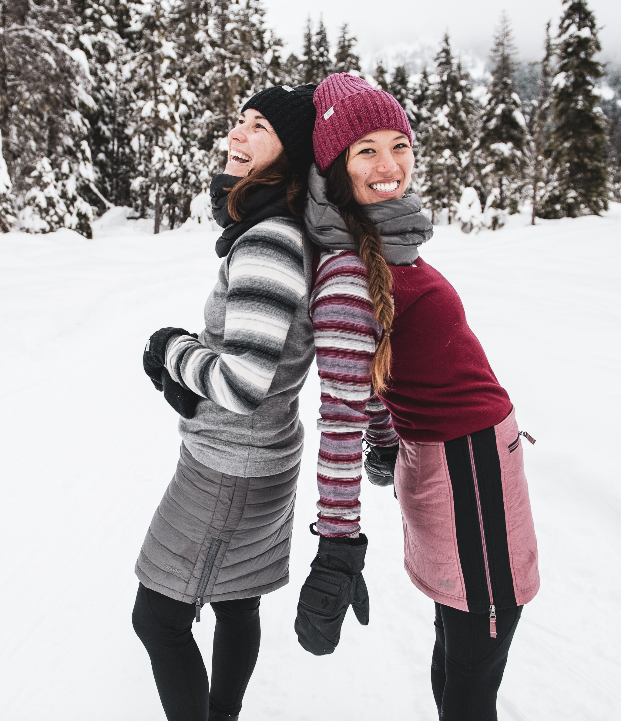 two friends laughing in the snow wearing skhoop outfits