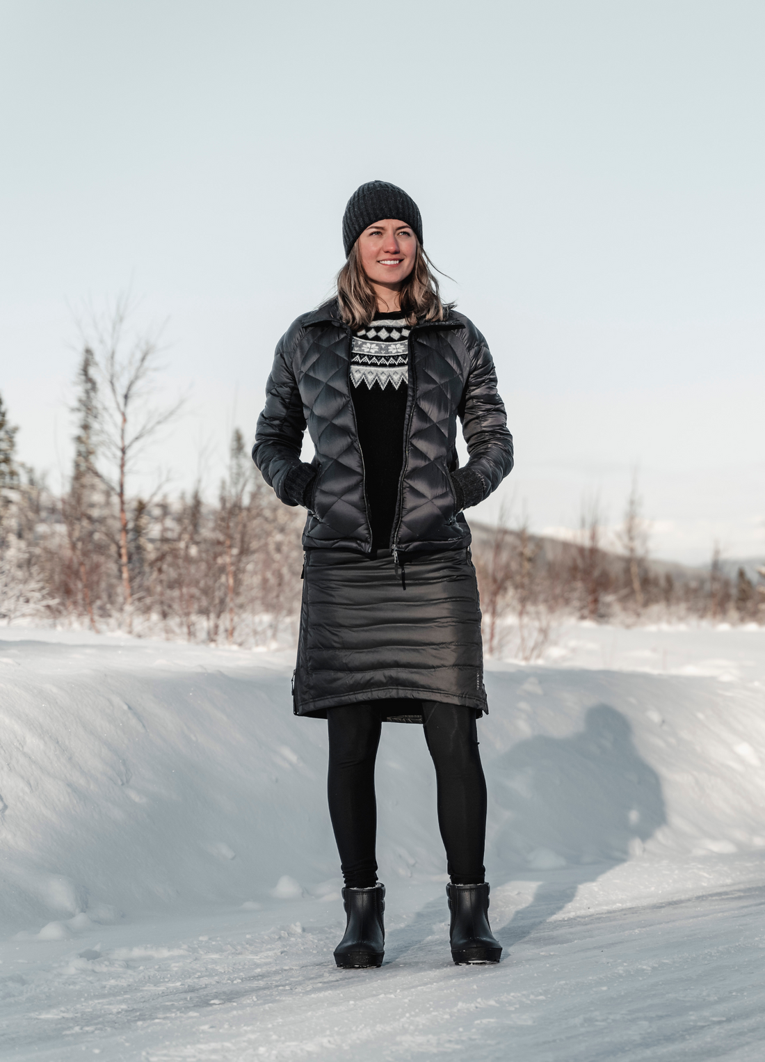 woman standing in the snow wearing black skhoop short down skirt